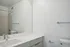 Modern bathroom featuring a sleek white countertop, large mirror, and minimalist fixtures.