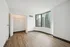 Chic apartment bedroom with sleek hardwood floors, expansive closet, and panoramic city views through large windows.