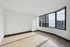 Bright, spacious apartment room with large windows offering stunning city and lake views, featuring elegant wood flooring and ample natural light.