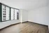 Bright and airy room with elegant hardwood flooring and large windows offering stunning city views.