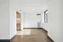 Bright, modern apartment interior with sleek hardwood flooring and ample natural light through large windows, featuring a cozy kitchen nook.