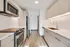 Modern kitchen with sleek stainless steel appliances, elegant wooden cabinetry, and chic laminate flooring.
