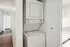 Modern apartment interior with a convenient in-unit stacked washer and dryer, highlighted by sleek wood flooring and bright, airy hallway.