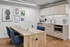 Modern office kitchen with sleek cabinetry, stylish art decor, and a spacious wooden meeting table with blue chairs.