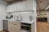Modern kitchen featuring sleek cabinetry, stainless steel appliances, and elegant hardwood flooring, with an inviting living area in the background.