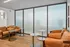 Elegant lounge area with plush leather seating, modern round tables, and large frosted windows providing soft natural light.