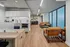 Modern apartment interior featuring an open-concept kitchen and living area with sleek cabinets, cozy seating, and large frosted windows.