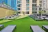 Luxurious rooftop area with sleek sun loungers on lush green artificial grass, surrounded by modern architectural buildings, perfect for relaxing and enjoying urban views.