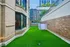 Charming urban patio with vibrant green artificial grass surrounded by elegant brick walls, perfect for outdoor relaxation.
