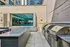 Luxurious outdoor space with modern grilling stations, sleek granite countertops, and a glimpse of a sparkling indoor swimming pool, offering a perfect blend of leisure and style.