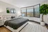 Bright and modern bedroom featuring a plush bed, large windows, and tasteful decor, offering a cozy and inviting atmosphere.