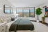 Inviting bedroom with large bay windows, stylish decor, and lush indoor plant for a serene atmosphere.