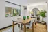 Elegant dining room with a wooden table, plush chairs, large window with greenery view, and stylish decor accents in a modern apartment.