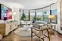Modern living room with large windows, elegant furniture, vibrant artwork, and abundant natural light creating an inviting atmosphere.