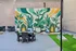 Chic outdoor patio with vibrant wall mural, featuring lush leafy plant designs and modern seating for a stylish, inviting atmosphere.