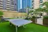 Vibrant urban rooftop terrace with a sleek ping pong table, modern lounge chairs, and lush greenery, offering a stylish outdoor oasis amidst skyscrapers.