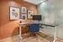 Modern workspace with a sleek adjustable desk and ergonomic chair, enhanced by chic artwork on a warm-toned wall.