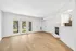 Bright open living room with pristine wood flooring, a cozy fireplace, and large glass doors offering a beautiful garden view.