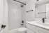 Modern bathroom with sleek white subway tiles, elegant black fixtures, and a spacious vanity.