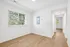 Bright, airy room with fresh white walls and warm wooden floors, enhanced by natural light streaming through wide windows with serene green views.