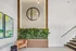 Elegant apartment lobby featuring modern wall art, lush greenery, and a cozy seating area with chic decor.