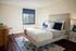 Bright and inviting bedroom with elegant decor, featuring a plush bed, stylish furniture, and a large window allowing natural light.