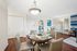Chic dining area with a stylish round table set for four, opening into a cozy living space with modern decor and vibrant artwork.