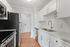 Modern kitchen with sleek stainless steel appliances, elegant white cabinetry, polished countertops, and warm wood flooring.