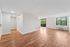 Bright, open-concept living space with elegant wood flooring and large windows offering lush green views.