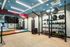 Modern fitness room with sleek equipment, mirrored wall, vibrant geometric design, and wood flooring.