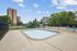 Inviting pool area with modern fencing and lush greenery, offering a refreshing outdoor retreat with scenic building views.