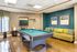 Chic recreation room with a sleek billiard table, cozy seating, and modern art accents.