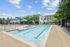 Inviting outdoor swimming pool with blue umbrellas and lounge chairs, surrounded by lush greenery and modern architecture, perfect for relaxation and leisure.