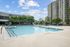 Inviting outdoor swimming pool surrounded by lush greenery and modern apartment buildings, perfect for relaxation and leisure.