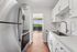 Modern kitchen with sleek stainless steel appliances, bright white cabinetry, and a picturesque view through the balcony doors.
