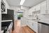 Modern kitchen with sleek white cabinetry, stainless steel appliances, and a bright, open view leading to a balcony.