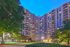 Elegant high-rise apartment building illuminated at dusk, surrounded by lush greenery and tranquil pathways.