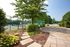 Inviting tennis court surrounded by lush greenery and a charming stone pathway, perfect for outdoor recreation.