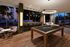 Luxurious recreation room with a stylish pool table, elegant seating, and floor-to-ceiling windows offering a picturesque city view.