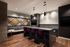 Modern lounge area featuring a sleek bar with purple chairs, cozy seating, and stylish pendant lighting.