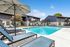 Inviting outdoor pool area with stylish lounge chairs and elegant blue apartments, perfect for sunbathing and relaxation.