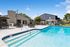 Inviting outdoor pool area with modern patio seating and a picturesque clubhouse backdrop under a clear blue sky.