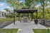 Charming outdoor gazebo with a built-in grill, surrounded by lush greenery and adjacent to a sparkling swimming pool.