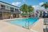 Inviting outdoor pool area featuring lounge chairs and a modern clubhouse, perfect for relaxation and social gatherings.