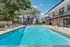 Inviting swimming pool with lounge chairs and umbrellas, surrounded by lush trees and modern apartment buildings.