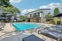Inviting outdoor pool area with sun loungers and modern clubhouse surrounded by lush greenery, perfect for relaxing and socializing.