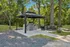 Charming outdoor gazebo with a modern grill and picnic area, nestled in a lush, green park setting.