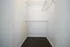 Spacious walk-in closet with white walls and practical shelving, ideal for organizing your wardrobe.
