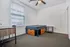 Bright and inviting bedroom with modern furniture, featuring a bed with built-in storage, a desk for work or study, and a ceiling fan for comfort.