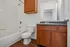 Modern bathroom with a sleek design featuring a tiled bathtub, wooden cabinetry, and elegant countertop, perfect for a stylish and functional living space.